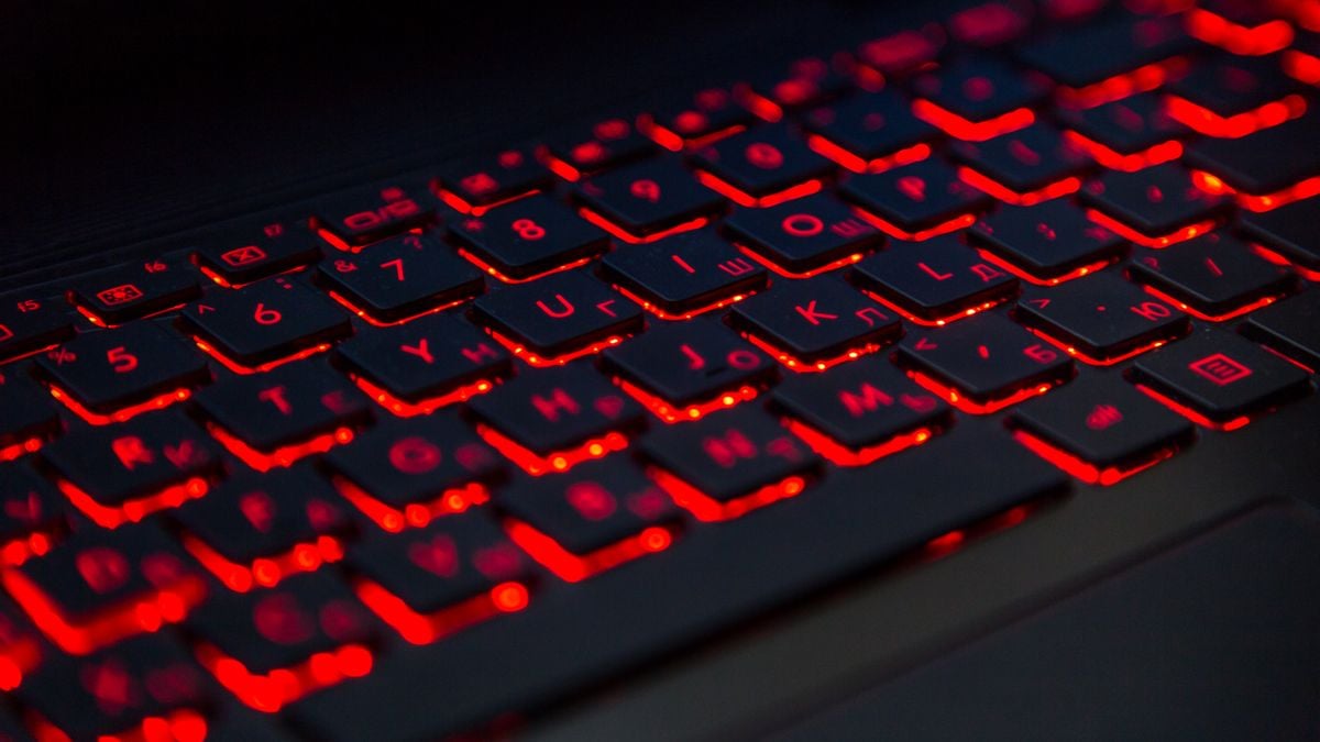 A laptop keyboard is backlit in red.